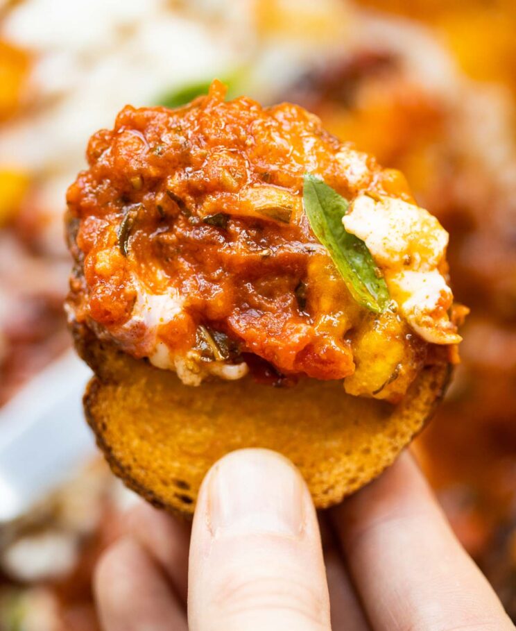 close up overhead shot of hand holding toast with tomato baked eggs on it
