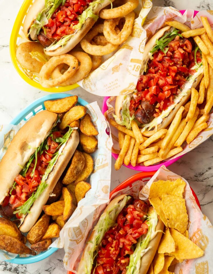 overhead shot of 4 blt hot dogs in baskets with different sides