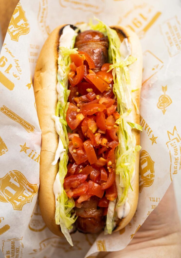 close up overhead shot of hand holding blt hot dog