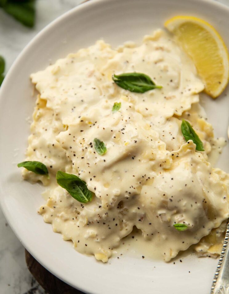 ravioli with lemon cream sauce served on small white plate garnished with basil