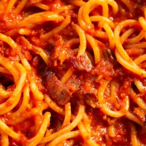 close up overhead shot of tomato bacon pasta in pan