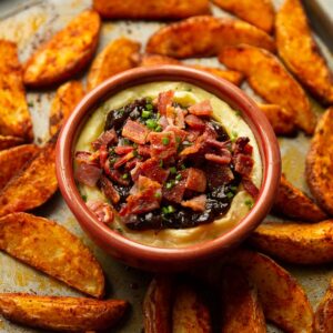 baked brie with bacon and caramelised onion on baking tray with potato wedges