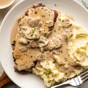 overhead shot of steak and mash on small white plate with silver fork